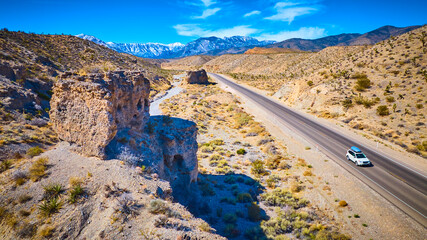 Aerial of Desert Road with SUV and Snow-Capped Mountains