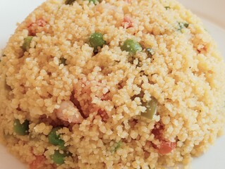 Couscous with vegetables  and  shrimps on a white plate.
