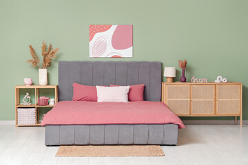 Interior of stylish bedroom with bed, wooden chest of drawers and bedside table