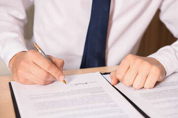 Man putting signature on document at table, closeup