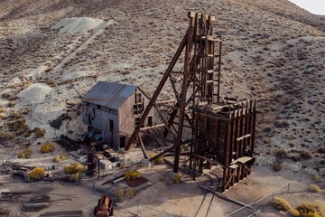 Fototapeta premium Abandoned mine site in Tonopah Historic Mining Park, Tonopah, Nevada, USA. The wooden headframe and mill building stand as relics of a bygone era, showcasing the region's rich mining history.