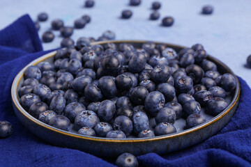 Plate with sweet fresh blueberries on blue background