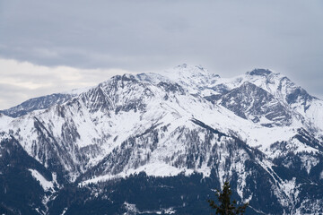 Cloudy January alpine landscape with mountains, trees, Austria.