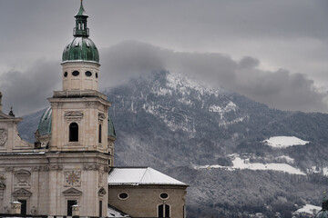 Cloudy Salzburg rooftop view, historical architecture, mountains, Austria winter.