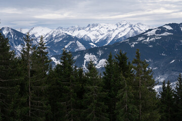 Cloudy January alpine landscape with mountains, trees, Austria.