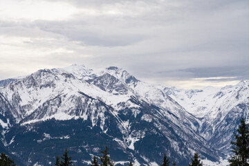 Cloudy January alpine landscape with mountains, trees, Austria.