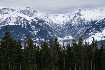 Cloudy January alpine landscape with mountains, trees, Austria.