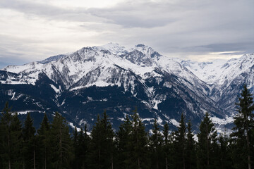 Cloudy January alpine landscape with mountains, trees, Austria.