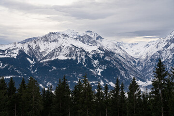 Fototapeta premium Cloudy January alpine landscape with mountains, trees, Austria.