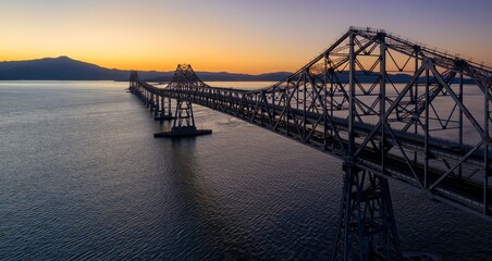 The Richmond-San Rafael Bridge spans San Pablo Bay in Richmond, California, USA, connecting counties. Cars travel across at sunset.