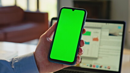 Unknown man holding mockup smartphone at desk closeup. Person watching screen