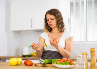 Portrait of disappointed young woman cooking at home kitchen