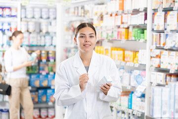 At pharmacy, female chemist shows cream to moisturize of sensitive skin and convinces doubter to purchase mini version of care product.