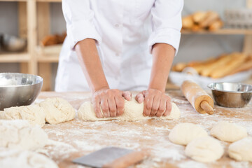 Female baker rolling out raw dough close-up