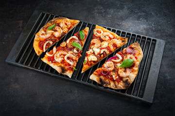 Traditional Italian pinsa bread prosciutto e salsa di pomodoro sliced with seafood, buffalo mozzarella and tomato sauce served as close-up on a rustic cast iron grillage