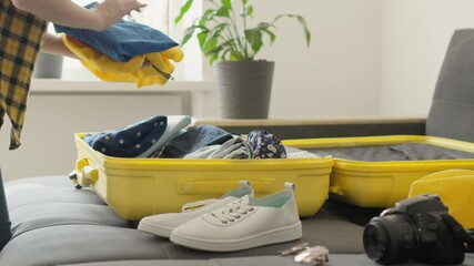 A person eagerly packs a sunny yellow suitcase with clothes and essentials, anticipating an exciting trip. The bright outdoor setting amplifies the adventurous spirit of the journey ahead