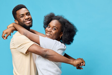 Obraz premium Happy young couple embracing against a vibrant blue background, showcasing joy and love in casual clothing, perfect for celebrating relationships and connection