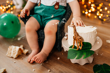 A cheerful baby enjoying a festive celebration with cake and decorations in the background.