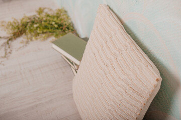 A cozy scene with a soft pillow, books, and delicate flowers arranged on the floor, creating a warm and peaceful atmosphere.