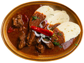 Meat goulash served with dumplings and vegetables, Slovak cuisine dish. Isolated over white...
