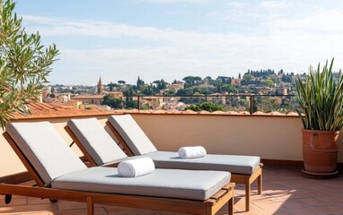 Fototapeta premium A serene rooftop scene featuring wooden lounge chairs with rolled towels, overlooking a picturesque landscape of greenery and distant buildings under a bright sky.