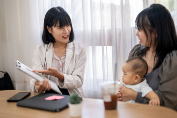 Obraz premium A woman is talking to a baby while holding a tablet