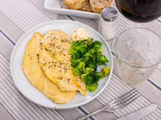 Stewed chicken fillet with spices and fresh broccoli on a white plate. Low-calorie protein lunch with vegetables