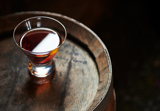 Whiskey cocktail sitting on top of an old whiskey barrel 