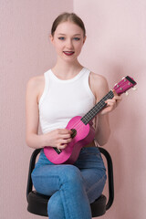 Sweetie female musician is practicing ukulele and looking at camera. Woman's performance exudes...