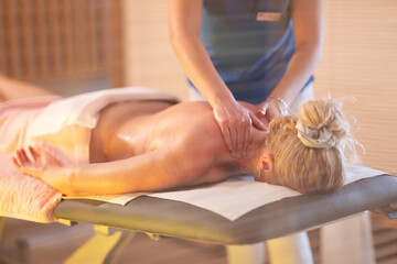 Relaxing Back Massage in a Spa Setting. A professional massage therapist in a blue uniform provides...