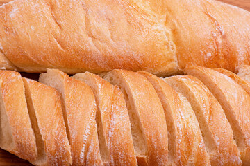 Wheat baguette sliced and whole close-up as a background.