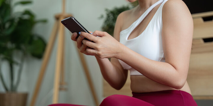 Yoga and Mindfulness. A woman engaging in yoga practice while checking her phone for guidance.