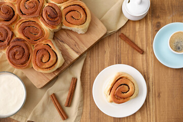 Freshly baked cinnamon rolls, spices and coffee on wooden table, flat lay