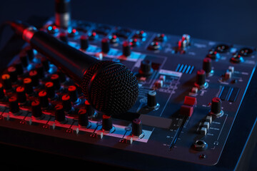 Professional mixing console with microphone on table in neon lights, closeup