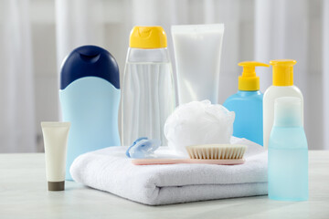 Baby cosmetic products, towel and brush on light wooden table indoors, closeup