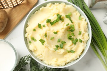 Delicious mashed potato with green onions served on white marble table, flat lay