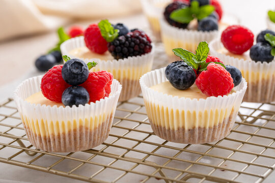 Mini cheesecakes baked in a muffin pan topped with fresh berries