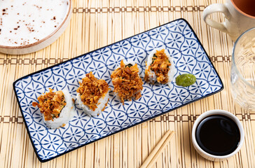 Restaurant serves food on bamboo mat - set of crunch California rolls made from of avocado, salmon, cheese and decorated with fried puffed rice. Widely known East Asian food, oriental restaurant