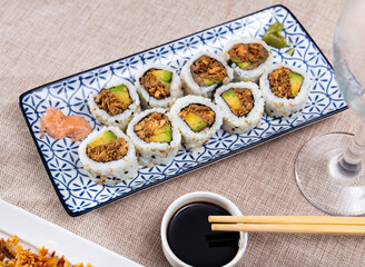 Beautifully plated Sake Cooked Roll with fried salmon, avocado, and crispy fried onion, served with...