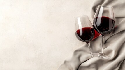 Elegant red wine glasses on a soft fabric background with copyspace