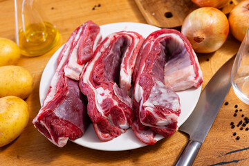 Table is laid out with products for cooking lunch, baked meat and side dishes. Raw beef ribs on...