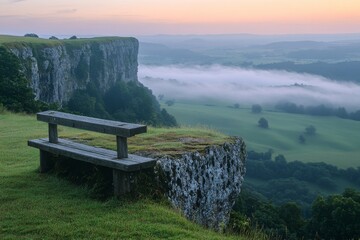 Scenic morning view from cliff with bench overlooking foggy valley