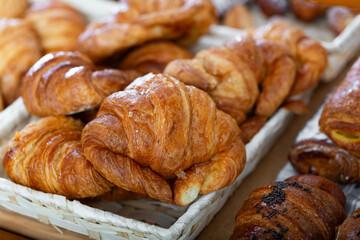 Delicious croissants with butter on the shelf in the bakery. Freshly baked breakfast rolls. French croissant on the counter
