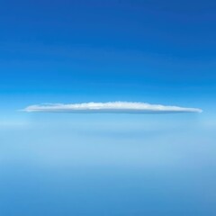 A lone stratus cloud floats across the horizon, its flat base merging with the blue, merge, solitary