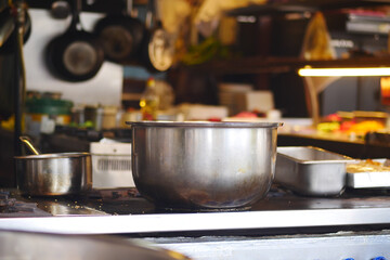Busy kitchen preparation with steel pots and cooking equipment