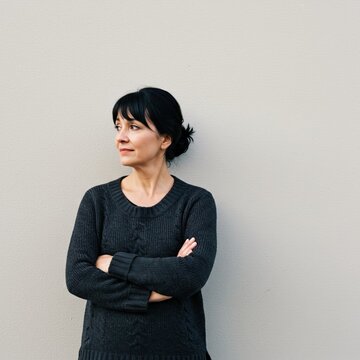 Confident Person in Gray Sweater Posing Against Neutral Background for Thoughtful and Contemplative Imagery
