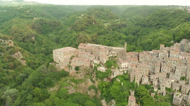 Aerial summer afternoon view of Sorano. Rooftops of an ancient medieval hill town hanging from a tuff stone over the Lente River. Etruscan heritage. Province Grosseto, Tuscany, Italy.