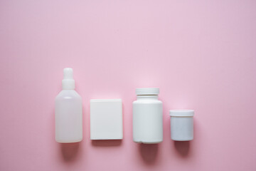 Here is a fascinating collection of various cosmetic and pharmaceutical containers elegantly displayed against a soft pink background, creating a visually appealing composition