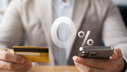 Young man using credit card and smartphone with 0% interest symbol shopping online, 0% minimum...