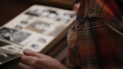 close-up male hands are carefully flipping through pages an old album with photos in blur. concept memories and nostalgia for past. shoulder over view.